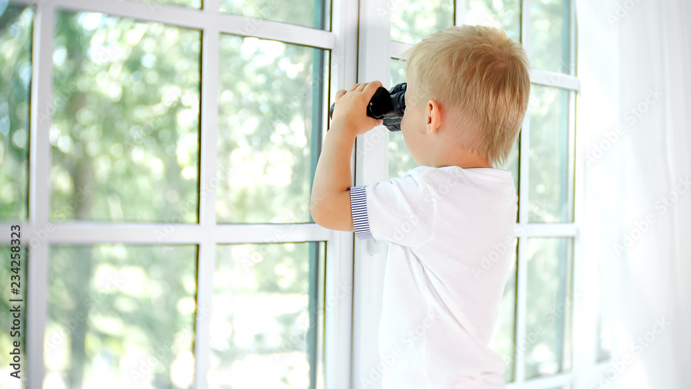 Little curious boy looking in window with binocular Little curious boy looking in window with binocular