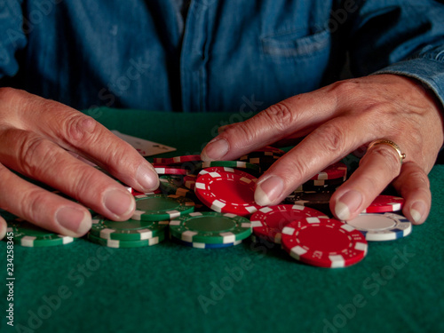 A person playing poker betting poker chips of various colors © anuskiserrano
