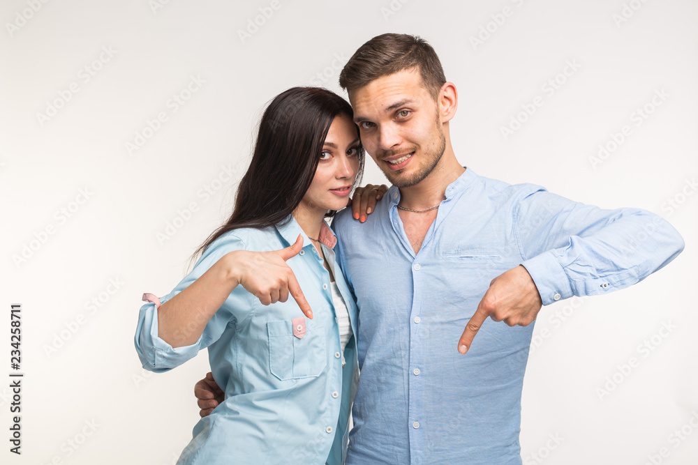 People and gesture concept - young pretty woman and handsome man pointing down over white background People and gesture concept - young pretty woman and handsome man pointing down over white background