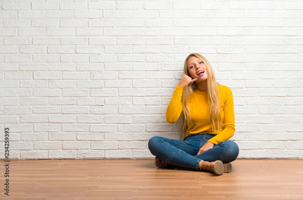 Young girl sitting on the floor making phone gesture. Call me back sign Young girl sitting on the floor making phone gesture. Call me back sign
