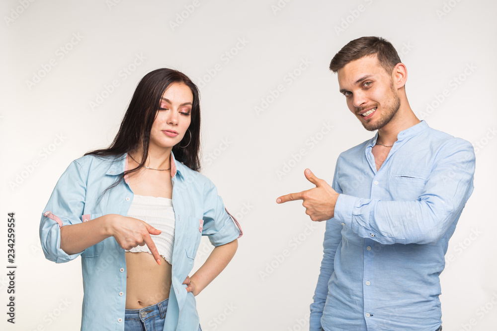 People and gesture concept - young pretty woman and handsome man pointing down over white background People and gesture concept - young pretty woman and handsome man pointing down over white background