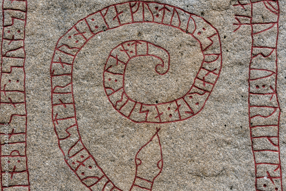 Close up of an old rune stone with red runes in the shape of a snake Close up of an old rune stone with red runes in the shape of a snake