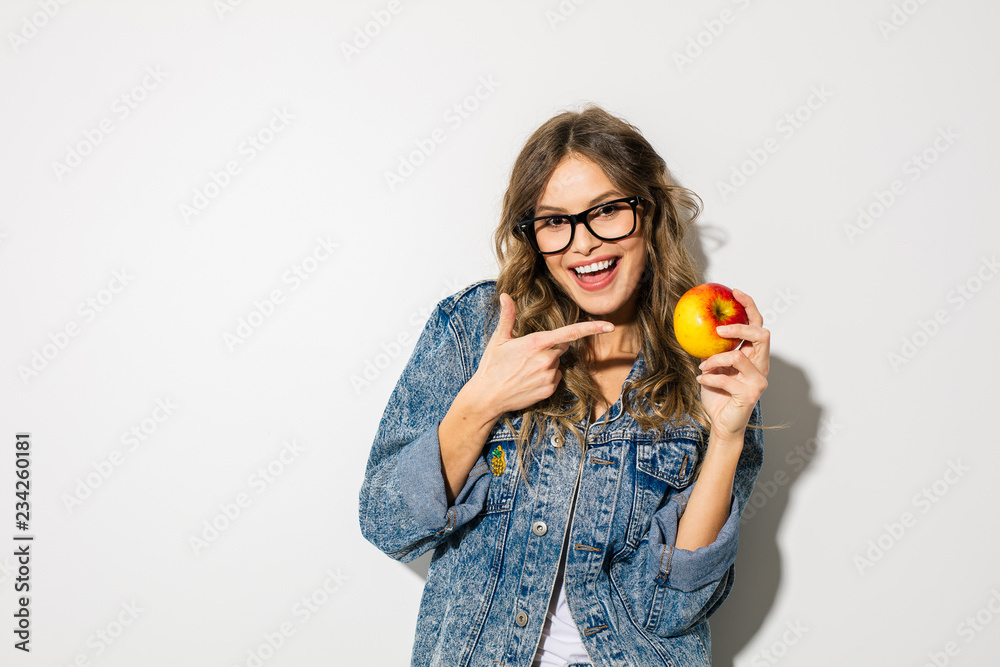 young trendy woman in jeans outfit posing on white with an apple young trendy woman in jeans outfit posing on white with an apple