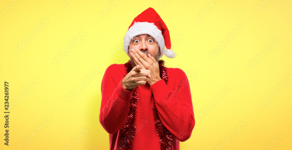 Man with red clothes celebrating the Christmas holidays pointing with finger at someone and laughing on yellow background Man with red clothes celebrating the Christmas holidays pointing with finger at someone and laughing on yellow background