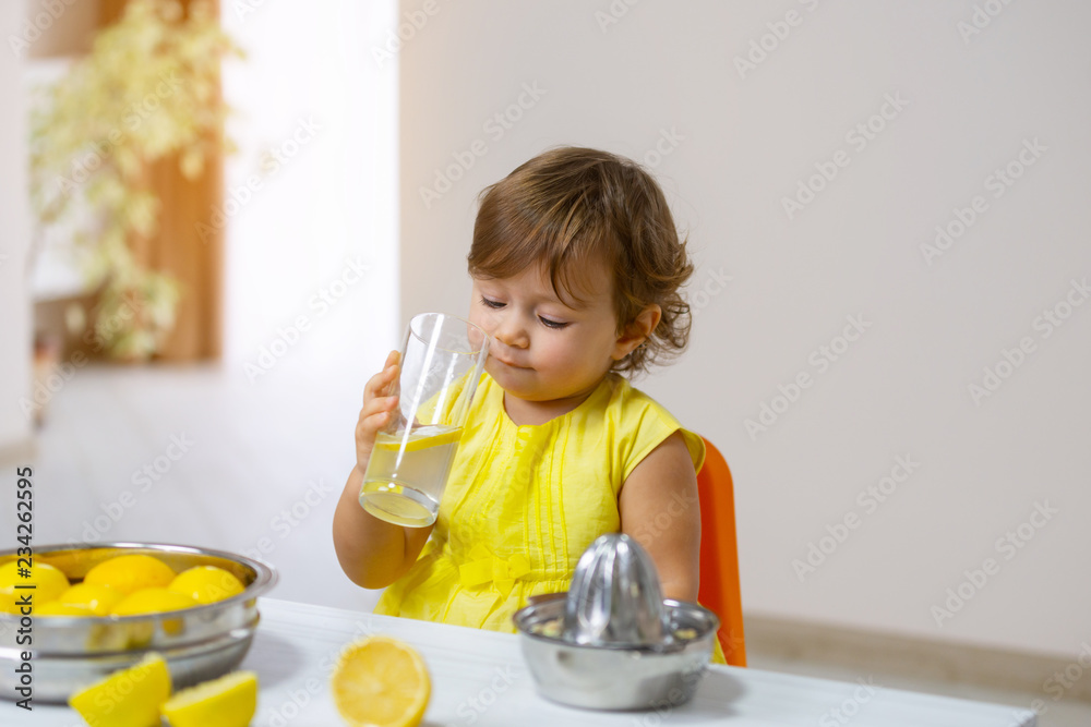 A little girl in a yellow dress tastes the cooked lemonade. A little girl in a yellow dress tastes the cooked lemonade.
