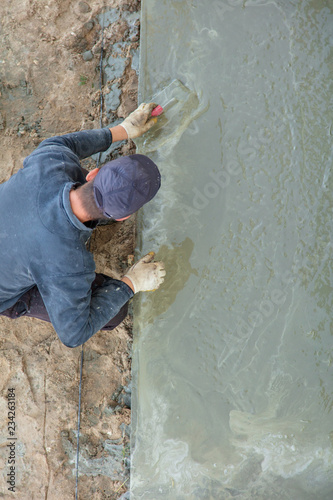 Workers pour concrete solution at a construction site