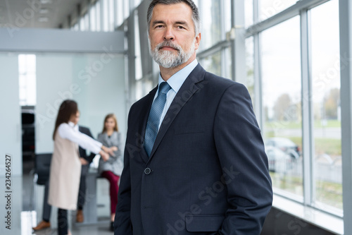 Businessteam in office, Happy Senior Businessman in His Office is standing in front of their team.
