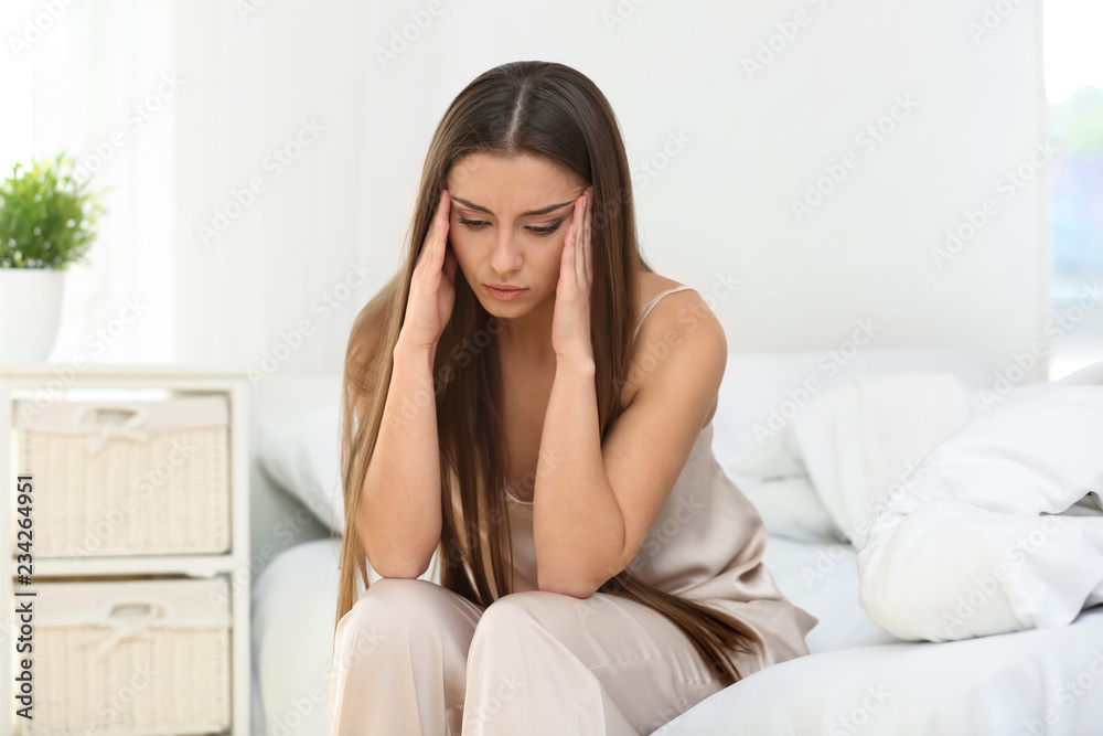 Woman suffering from headache in bedroom Woman suffering from headache in bedroom