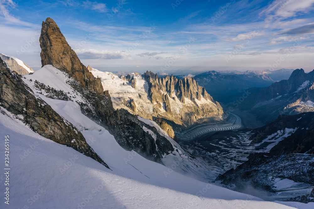Obraz premium View of a high alpine landscape of Mont Blanc Massif, the Aiguilles du Chamonix and a glacier. Great alpine sunset light, snow, high rocks and summits and peaks. France and Italy.