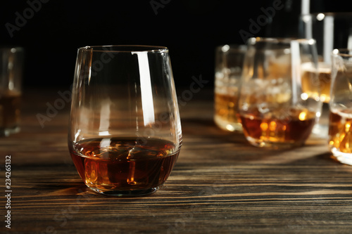 Glasses of whiskey on wooden table against black background