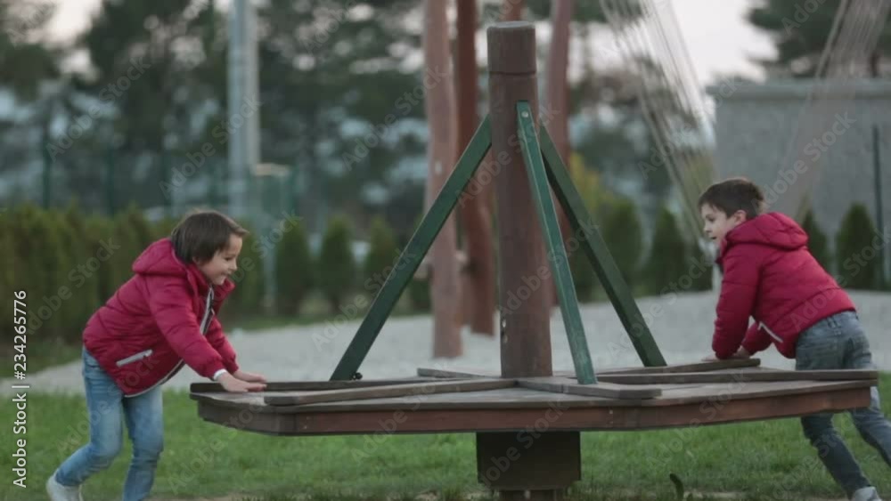 Happy children, brothers, playing on a merry go round carousel outdoors, autumntime