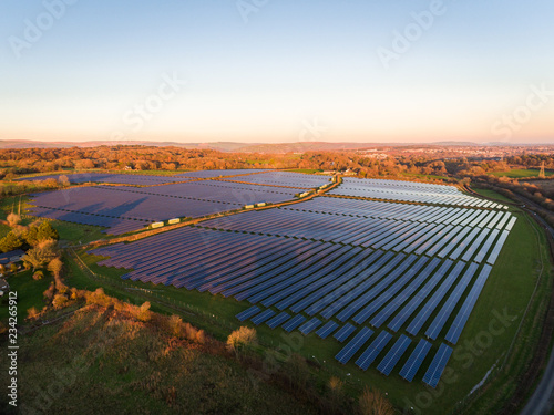 Aerial drone view of solar panels at a solar energy generation farm at Sunset in South Wales, UK