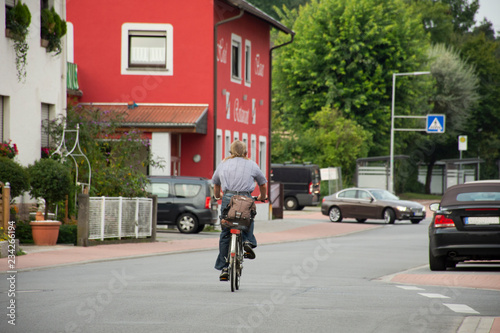 German man people biking bicycle on Sandhausen street with traffic road in Heidelberg, Germany