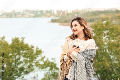 Beautiful young woman with thermos resting outdoors
