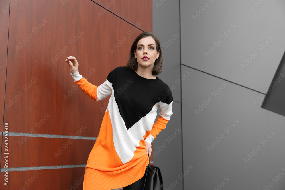 Beautiful fashionable woman near wall outdoors