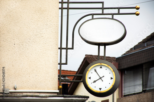 Classic retro vintage metal clock hanging on front of building at Sandhausen district in Heidelberg, Germany photo