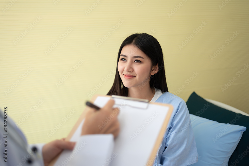 Asian Woman patient during Doctor writing something on a clipboard. Asian Woman patient during Doctor writing something on a clipboard.