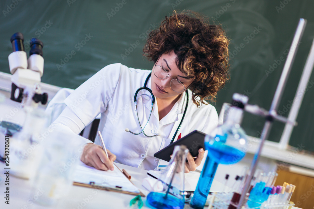 Portrait of confident female scientist working on digital tablet in chemical laboratory Portrait of confident female scientist working on digital tablet in chemical laboratory