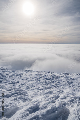 Mountain tops covered with snow above the white heavy clouds. © volff