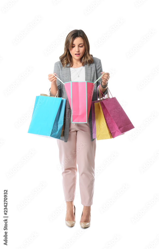 Beautiful young woman looking into shopping bag on white background