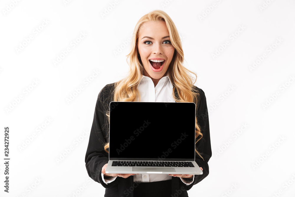 Photo of beautiful businesswoman wearing office suit smiling while holding laptop with black screen, isolated over white background in studio Photo of beautiful businesswoman wearing office suit smiling while holding laptop with black screen, isolated over white background in studio