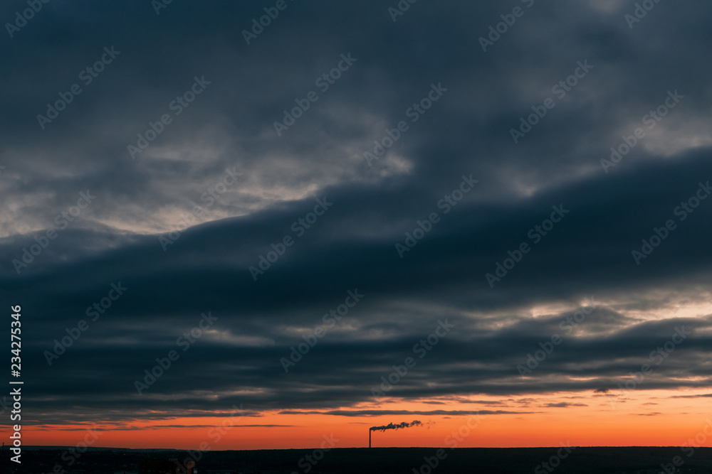 Beautiful landscape at sunset with clouds. View of the pipe with smoke Beautiful landscape at sunset with clouds. View of the pipe with smoke