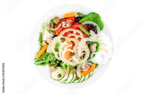 Vegan salad with tuna, olives, eggs, tomatoes, bell peppers and onions in a white plate isolated on white background. top view. flat lay