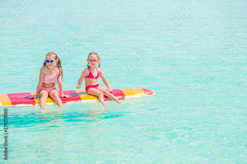 Little girls swimming on surfboard during summer vacation © travnikovstudio