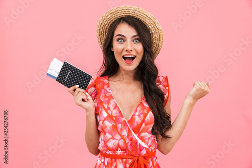 Emotional young woman posing isolated over pink background wall holding passport and tickets.
