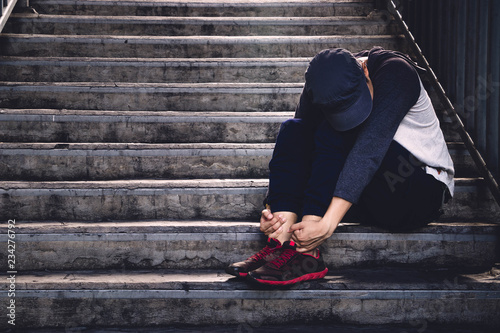 Young man with depression sitting and hugs his knees up.  major depressive disorder. Sad depressed. photo