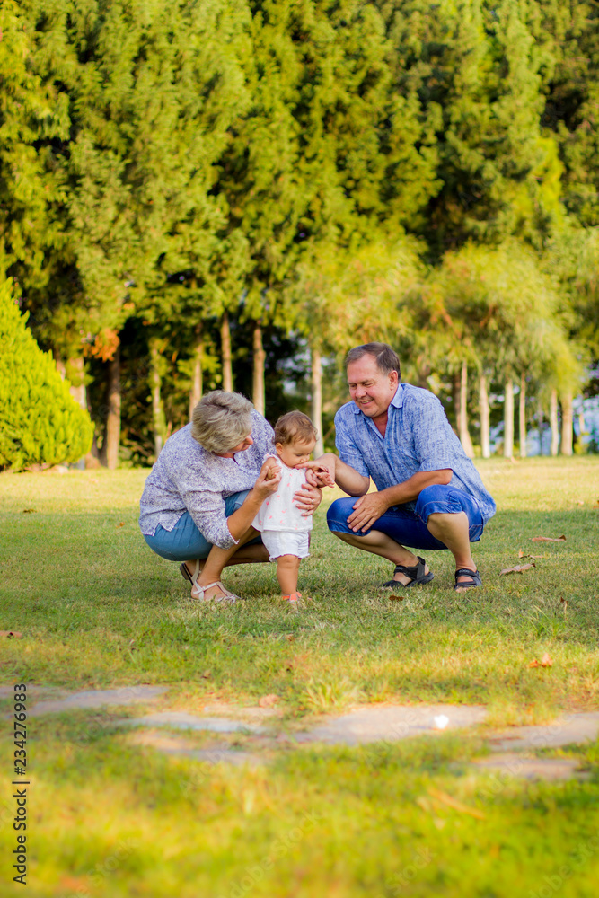 Fototapeta premium Young grandmother and grandfather on a walk with their granddaughter