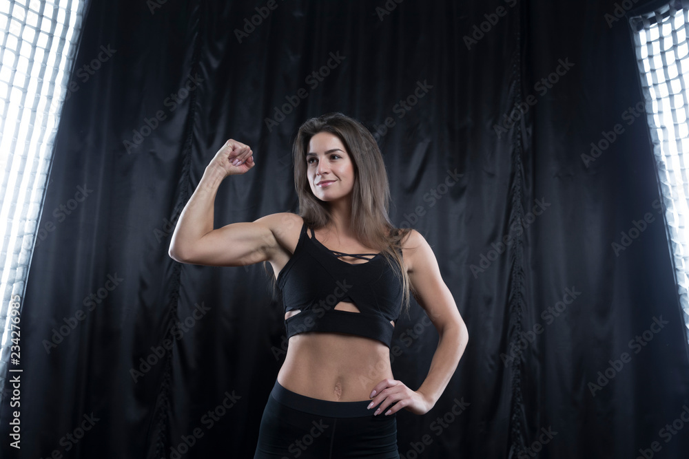 Fitness model in black sports uniform posing on a dark background Fitness model in black sports uniform posing on a dark background