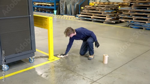 A young industrial worker cleaning-up a slip hazard in an industrial factory