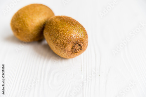 Two fresh kiwifruits on white wooden surface