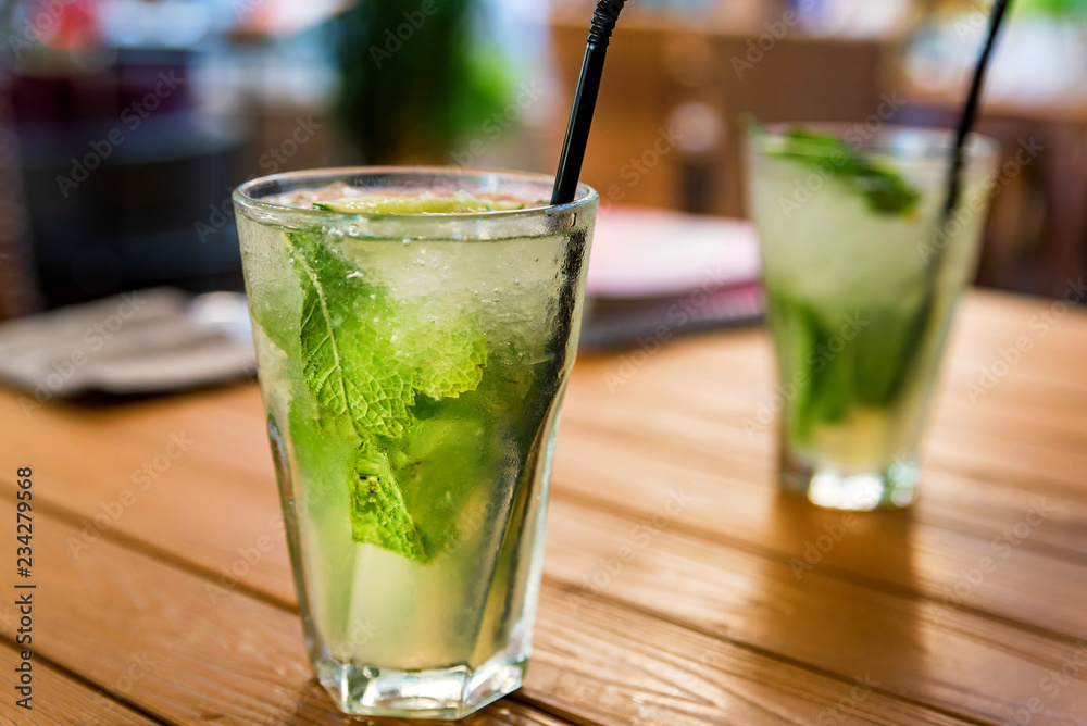 Two glasses of mojito cocktail with lime and mint on wooden table Two glasses of mojito cocktail with lime and mint on wooden table