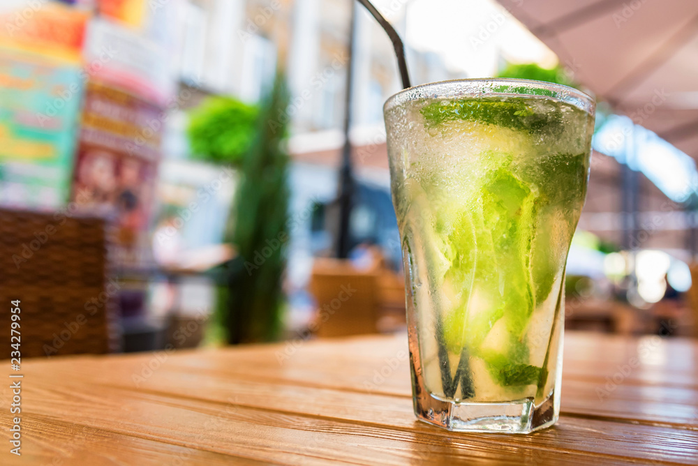 Mojito cocktail with lime on wooden table with blurred restaurant background Mojito cocktail with lime on wooden table with blurred restaurant background