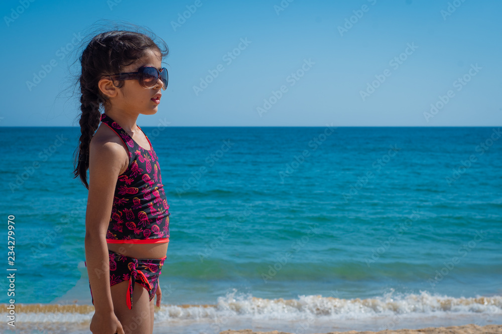Girl playing with racquet at a beach - horizon and sea visible in background - with copy space. Girl playing with racquet at a beach - horizon and sea visible in background - with copy space.
