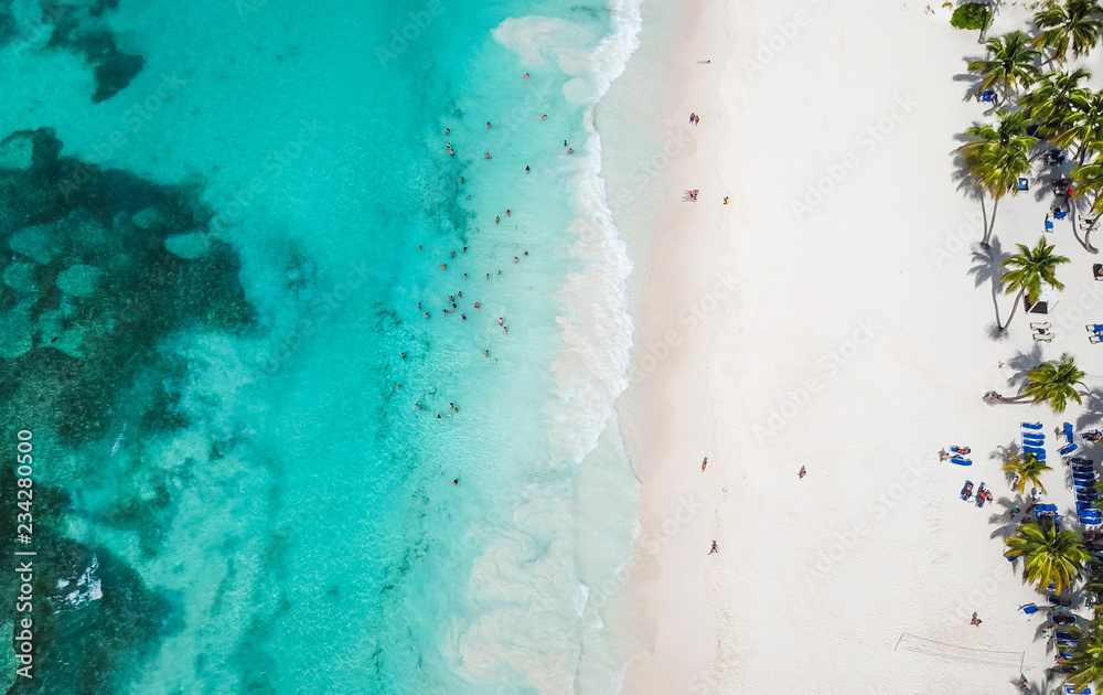 Incredible view of the white sandy beach from a bird's eye view. Top view of beautiful white sand beach with turquoise sea water and palm trees, aerial drone shot. 