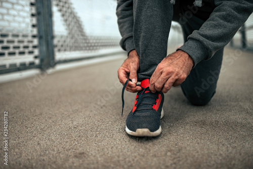 Senior man tying shoelaces before a run. Close-up.