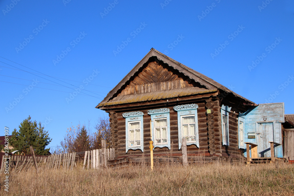 Typical old log house in the Russian village in late autumn against a blue sky Typical old log house in the Russian village in late autumn against a blue sky