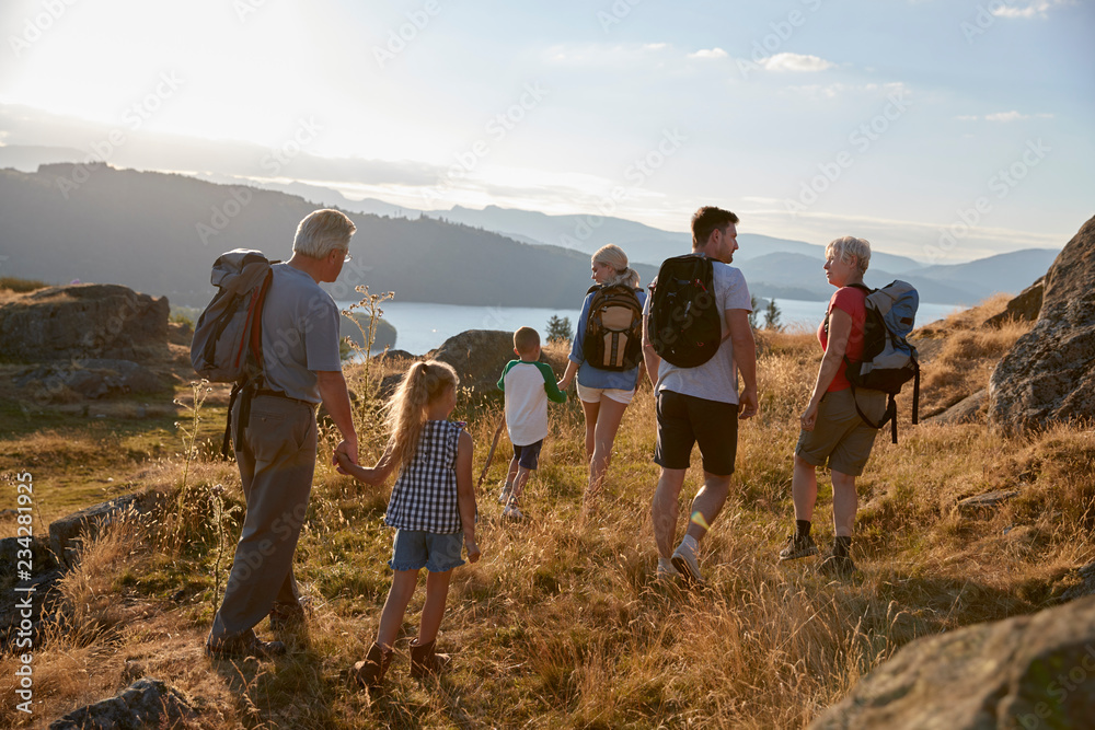 Rear View Of Multi Generation Family Walking On Top Of Hill On Hike Through Countryside In Lake District UK