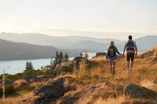 Photo Rear View Of Couple Walking On Top Of Hill On Hike Through Countryside In Lake D