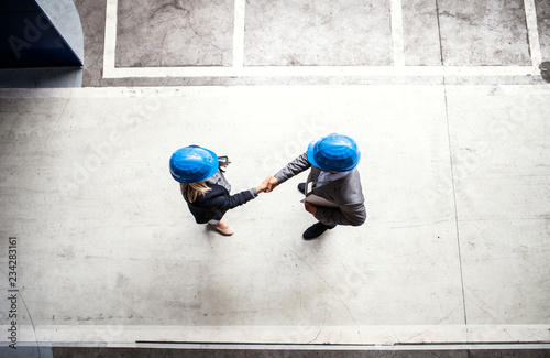 A top view of an industrial man and woman engineer in a factory, shaking hands. photo