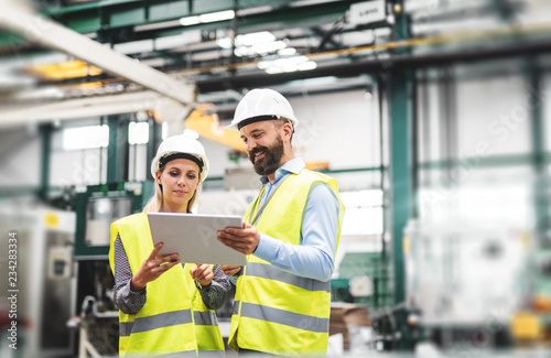 Foto A portrait of an industrial man and woman engineer with tablet in a factory, talking