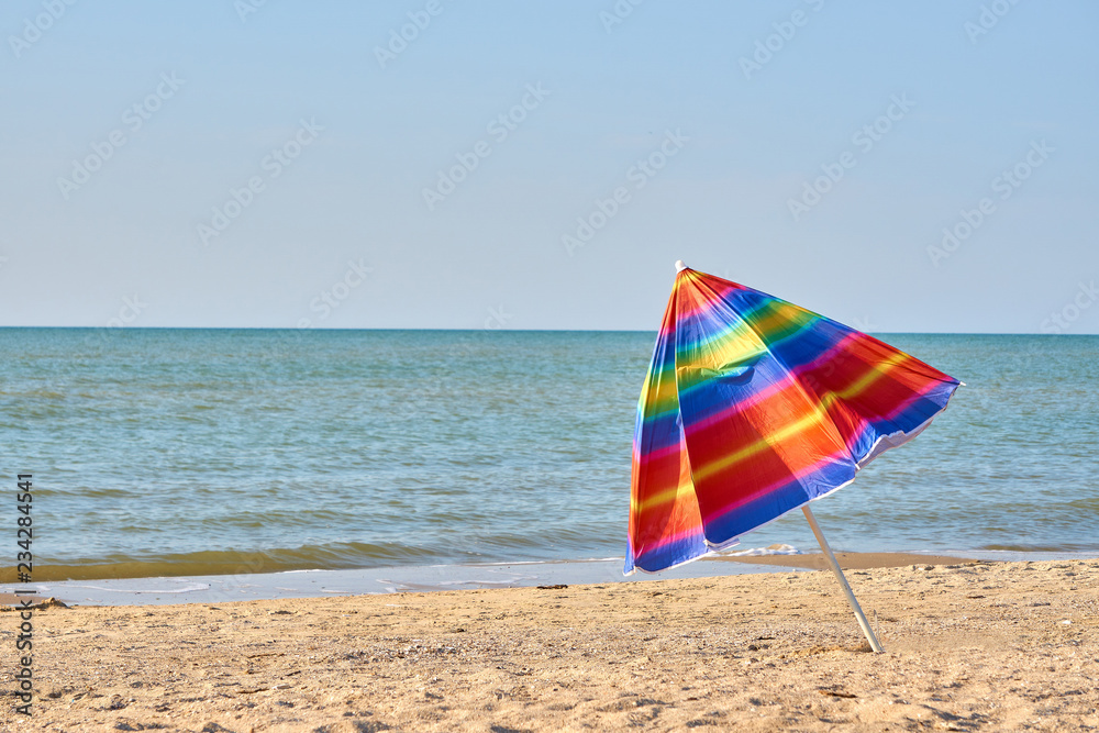 Folded colored beach umbrella on the beach. Closing of the holiday season