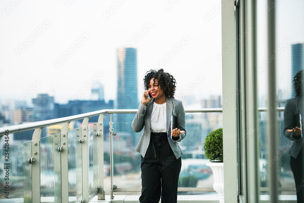 A portrait of a businesswoman standing on a terrace, making a phone call.