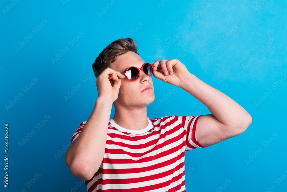 A young man with red sunglasses standing in a studio, looking up. A young man with red sunglasses standing in a studio, looking up.