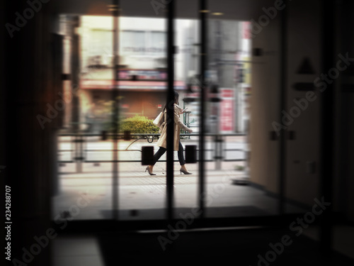 Photography Asian business woman walking on urban street while holding a mobile phone with blurred motion background