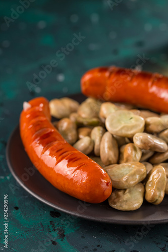 Closeup fried sausage in a frying pan, with herbs and spices. Selective focus.