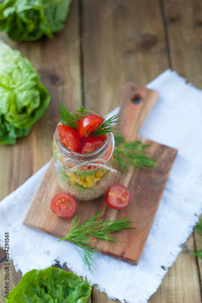 Salad in a jar with tomatoes, cabbage, cereals and corn. Delicious healthy food from spring vegetables.
